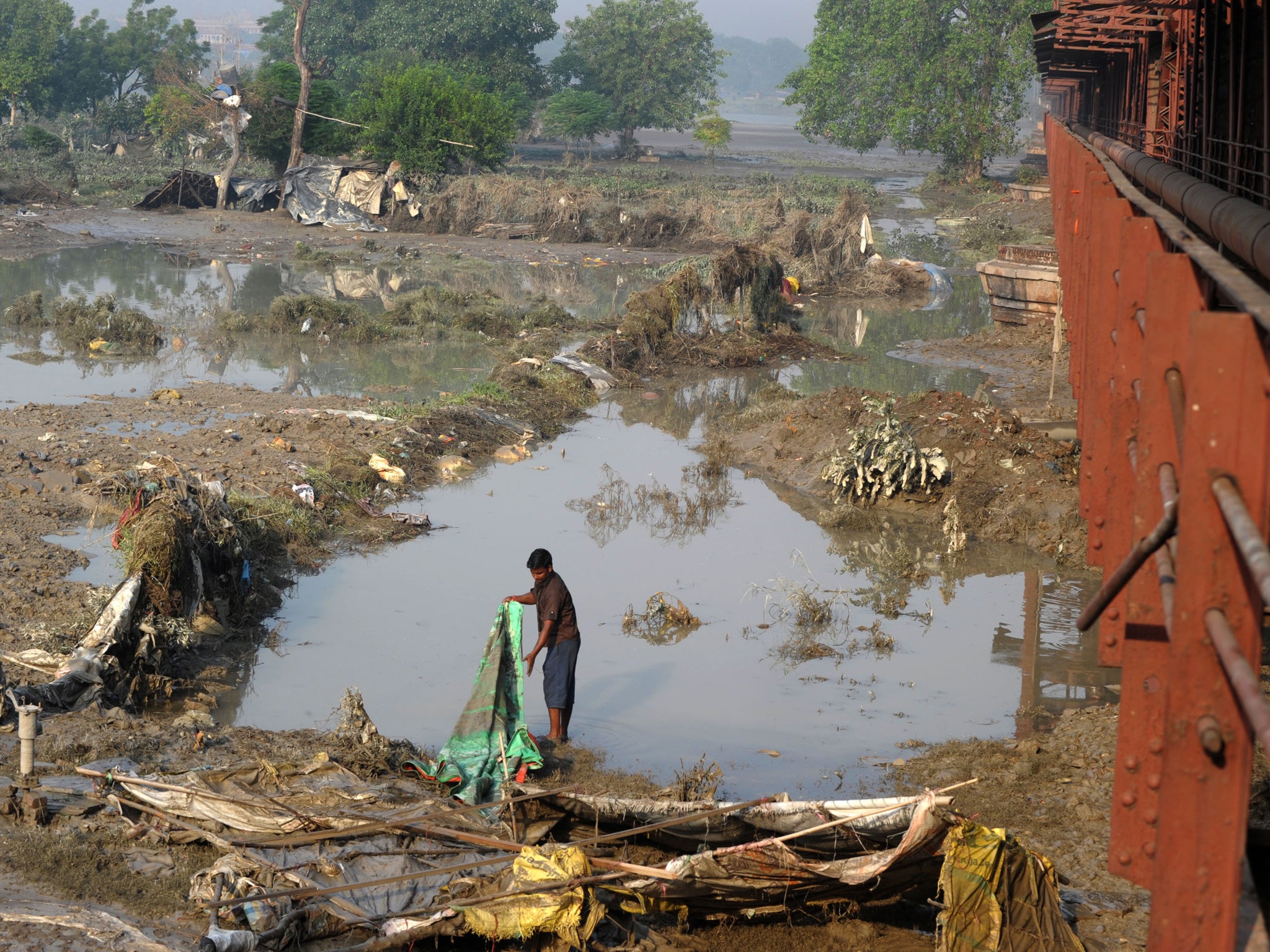 An Indian man evacuvated due to rising waters searches the banks of the Yamuna River in New Delhi, where nearly 5,000 people have been evacuated