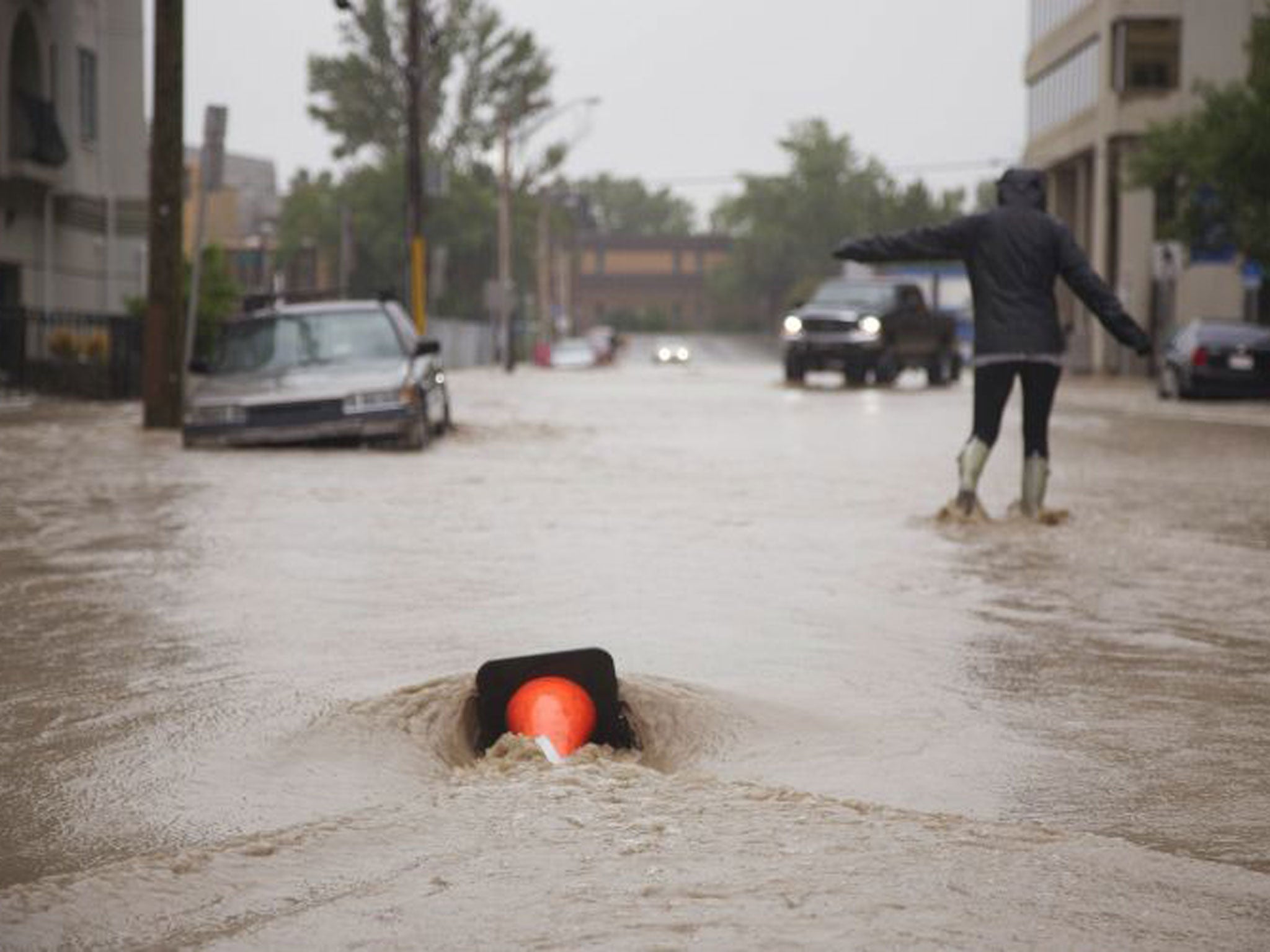 A woman attempts to walk down a flooded downtown street in Calgary, Alberta