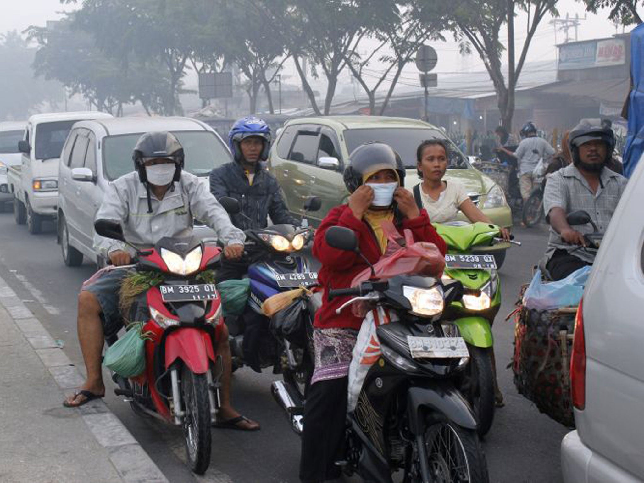 Indonesian motorists wear masks as haze continues to blanket the city