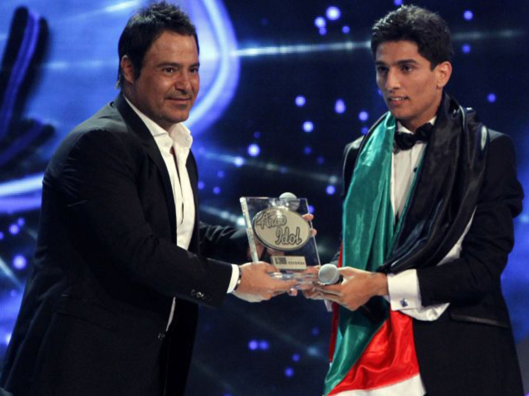 Mohammed Assaf, right, receives his trophy from Lebanese singer Assi al-Hallani after his win