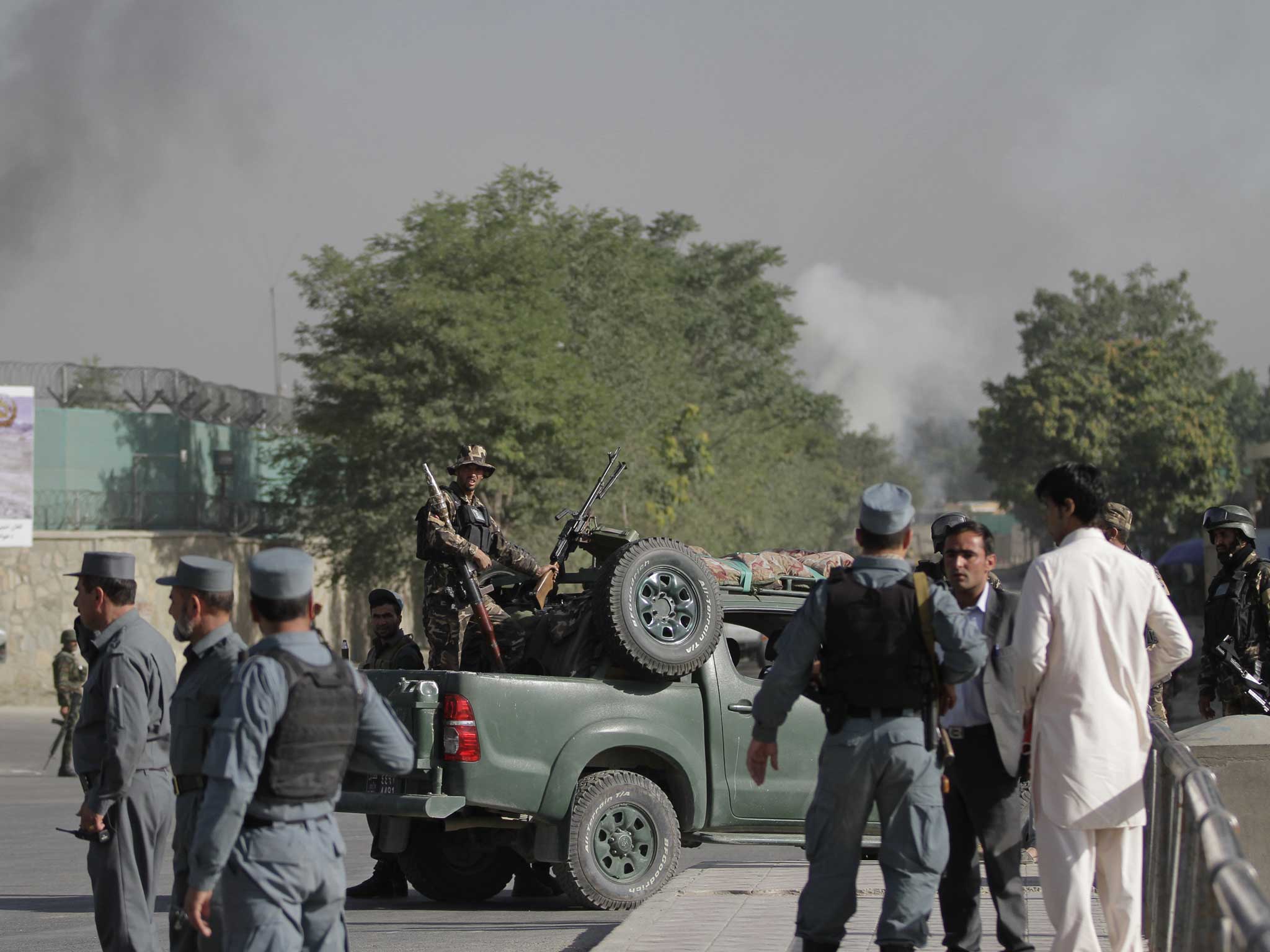 Afghan soldiers stand guard as smoke rises from the gate of the presidential palace in Kabul