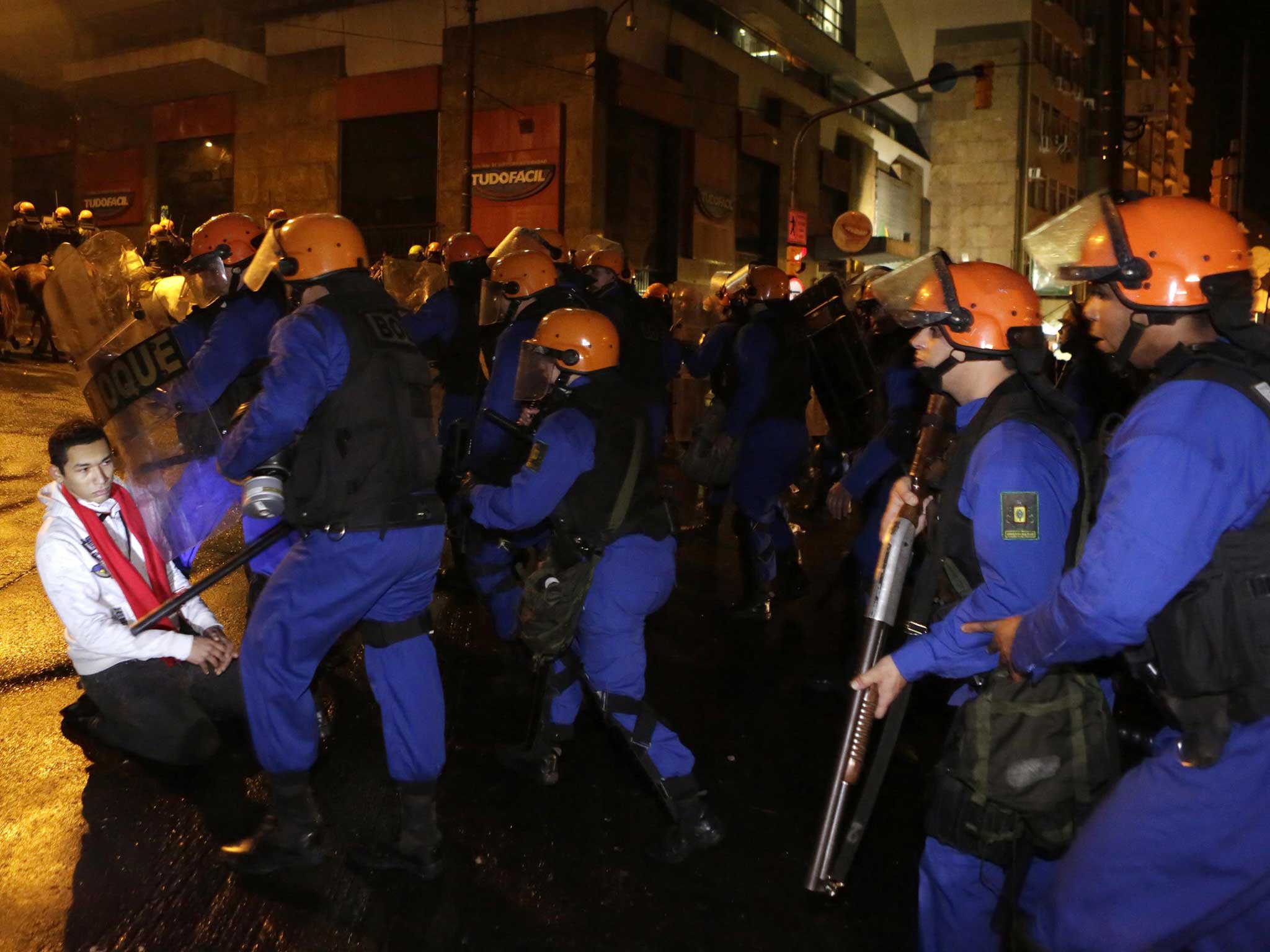 A demonstrator blocks riot police advancing on a protest march in Porto Alegre in Brazil