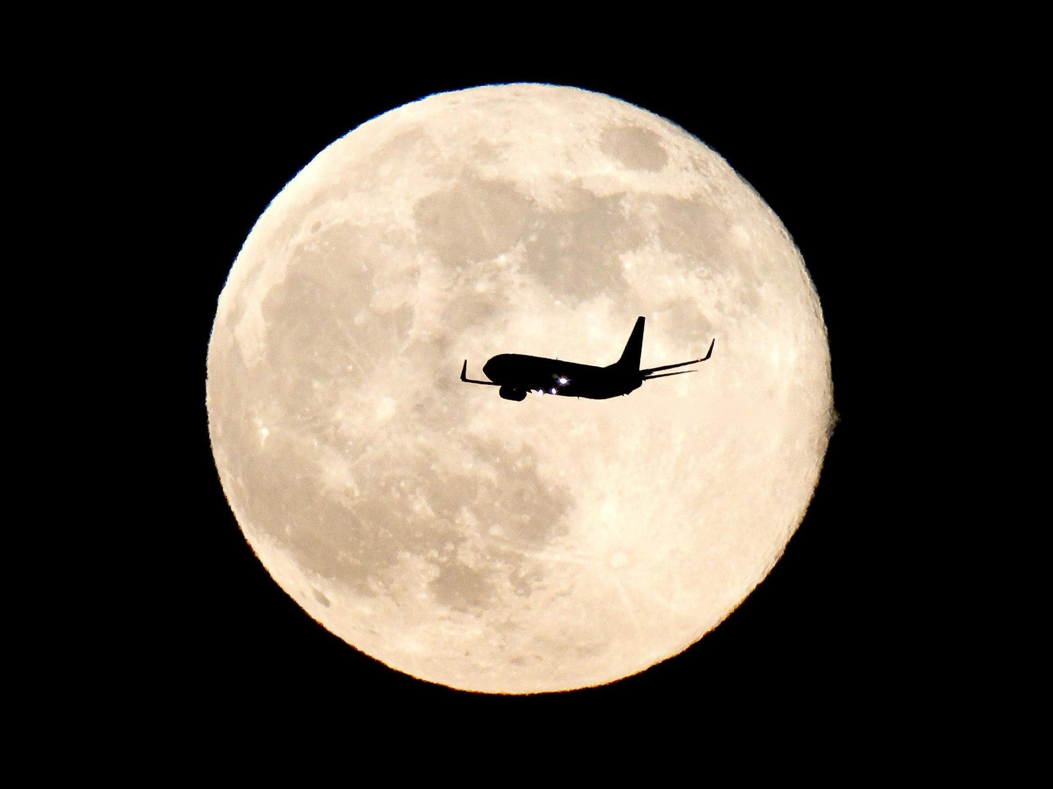 In airplane flies past the supermoon near Madrid, Spain.