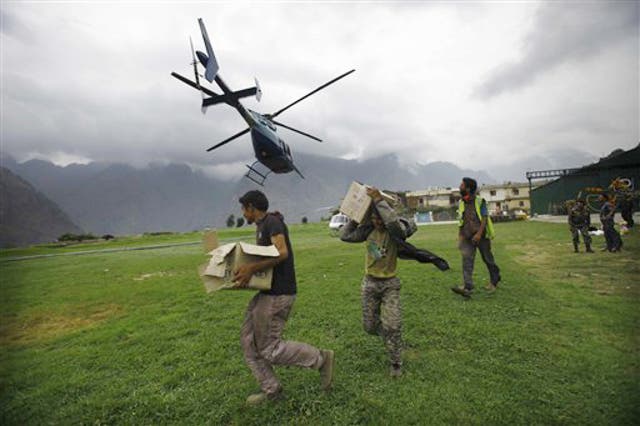Indian civilians get ready to load relief material for flood affected victims on a helicopter at a makeshift helipad at Joshimath, in northern Indian state of Uttarakhand