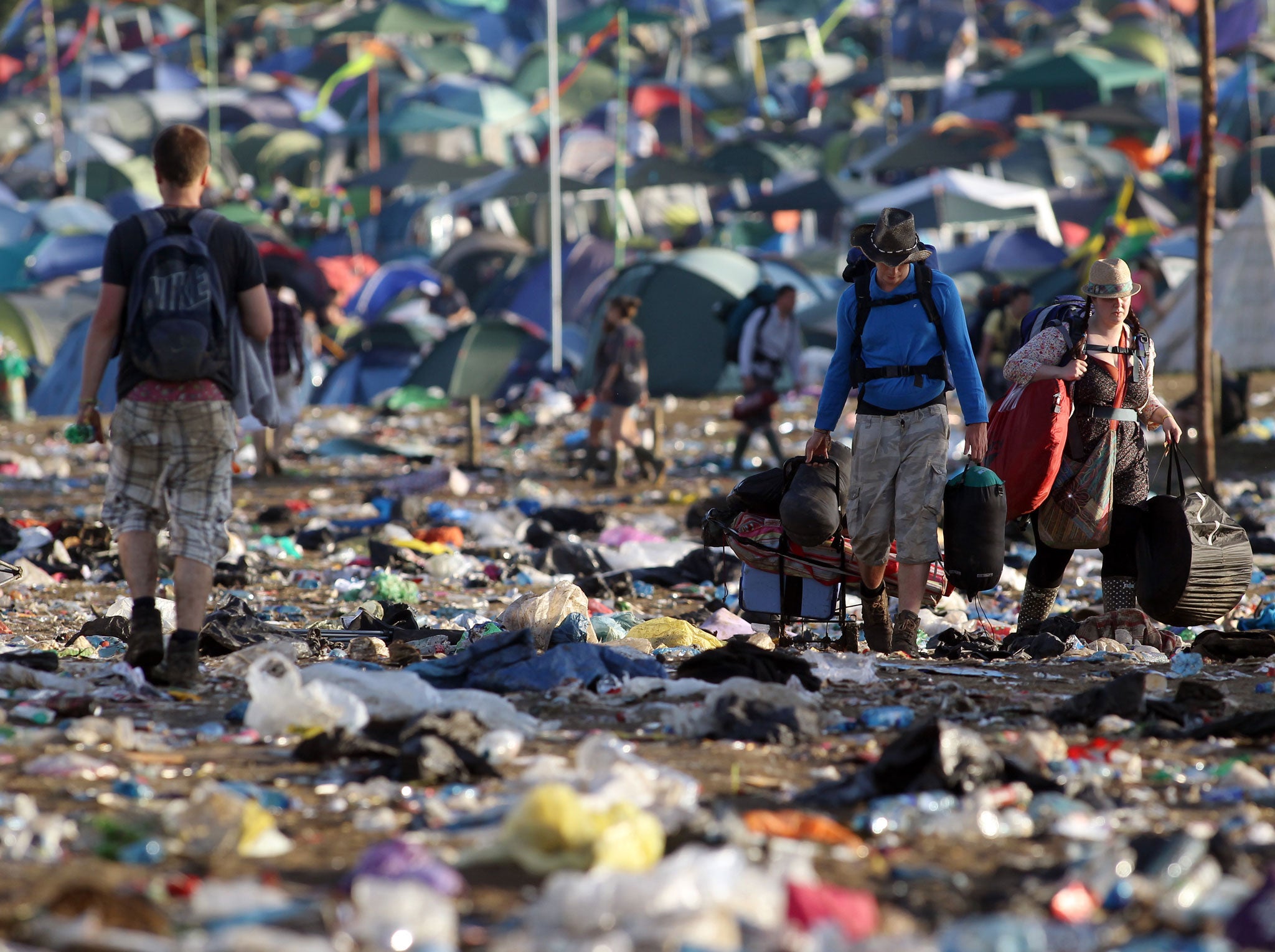 Festival-goers walk through rubbish close to The Pyramid Stage as they leave following the Glastonbury festival near Glastonbury, Somerset, on June 27, 2011.