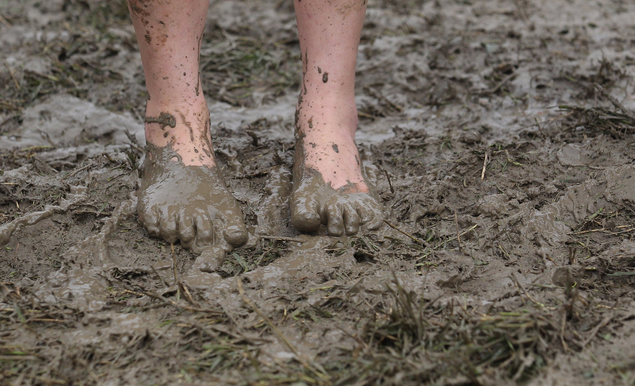 A festival attendee braves the mud as she arrives at the Glastonbury Festival site at Worthy Farm, Pilton on June 22, 2011