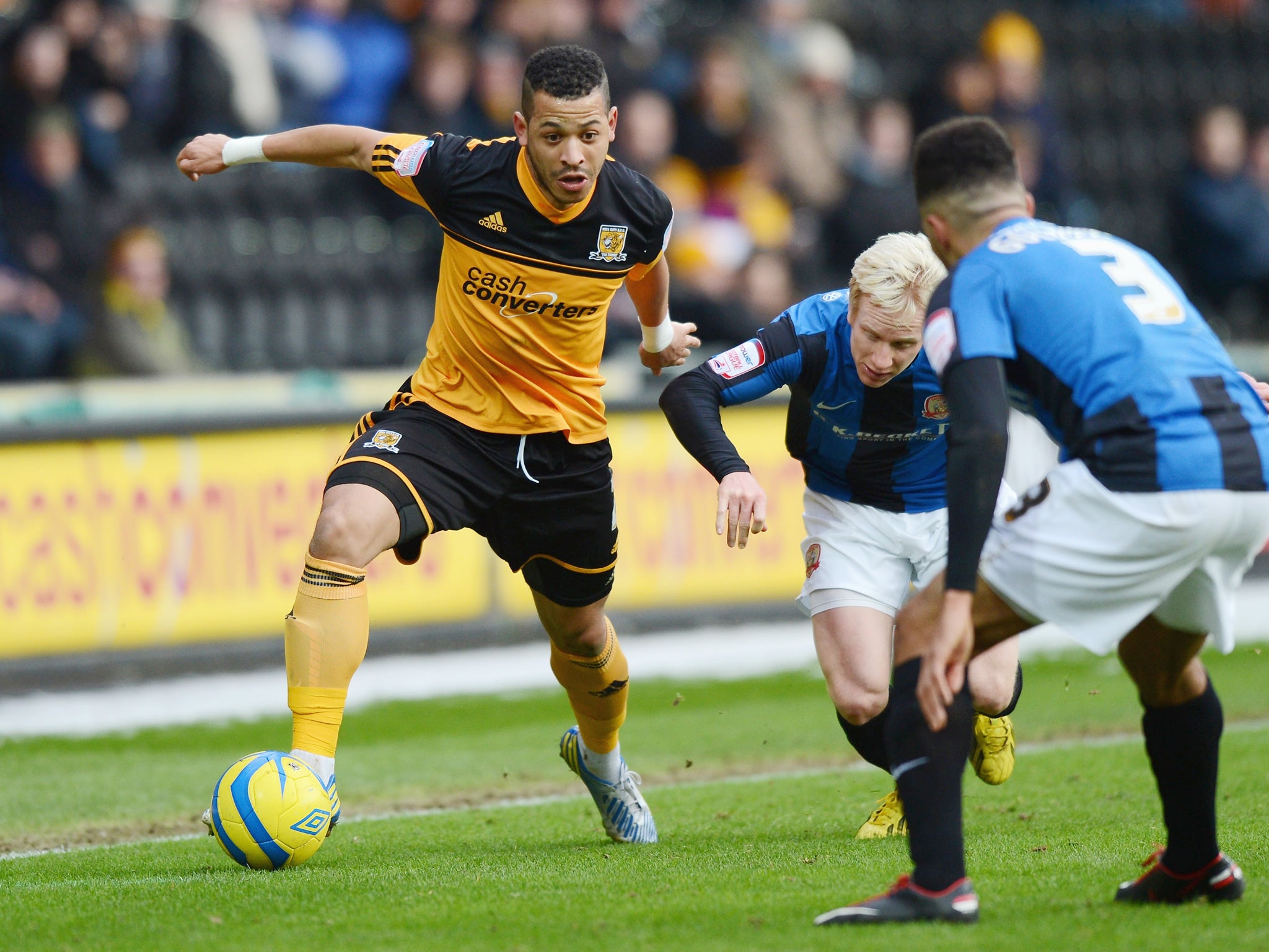 Liam Rosenior of Hull City passes David Perkins and Scott Golbourne of Barnsley during a FA Cup game