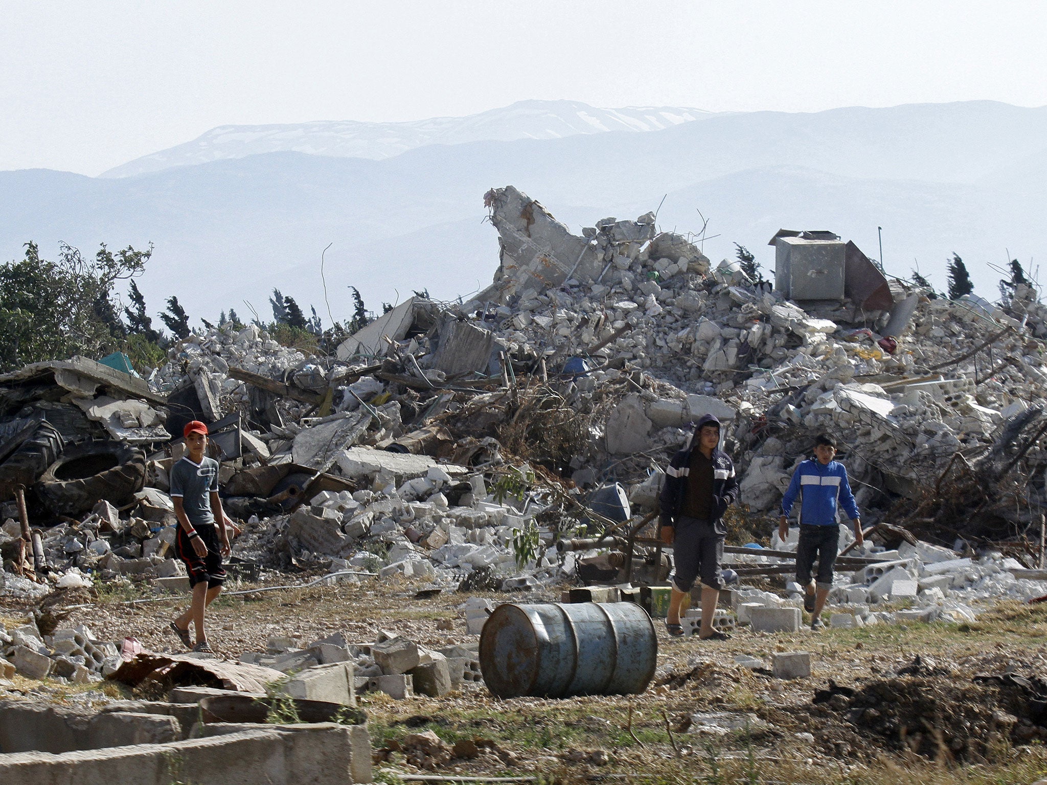 Syrian youths walk amongst the rubble in the village of al-Hamidiyeh, north of Qusayr, in Homs province