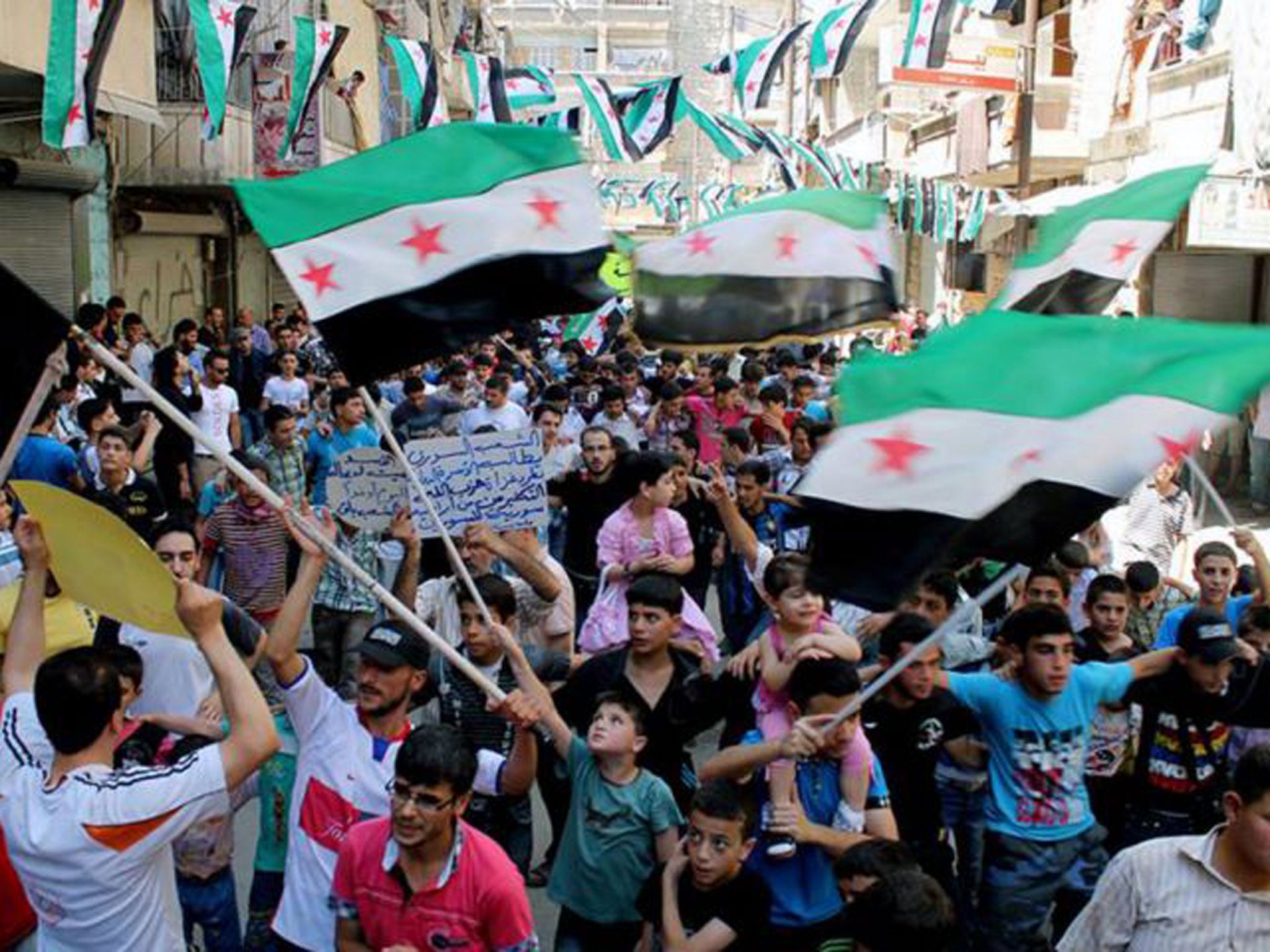 Anti-Syrian regime protesters holding Syrian revolution flags, during a demonstration in the neighborhood of Bustan Al-Qasr in Aleppo, Syria