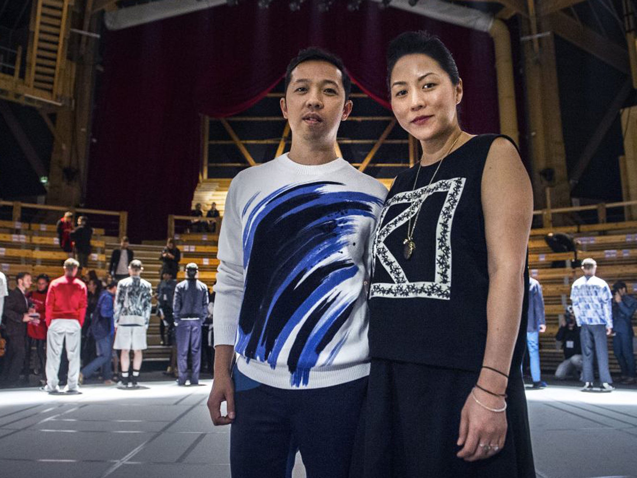 Designers Humberto Leon, left, and Carol Lim, right, pose for photographs with models in the background after presenting their Spring/Summer 2014 Men's Collection for Kenzo