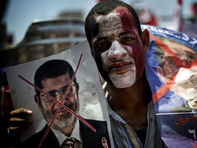 An Egyptian holds up posters during a protests against President Mohamed Morsi and the Muslim Brotherhood as they join thousands at Egypt's landmark Tahrir square