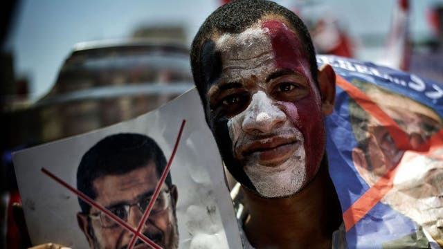 An Egyptian holds up posters during a protests against President Mohamed Morsi and the Muslim Brotherhood as they join thousands at Egypt's landmark Tahrir square