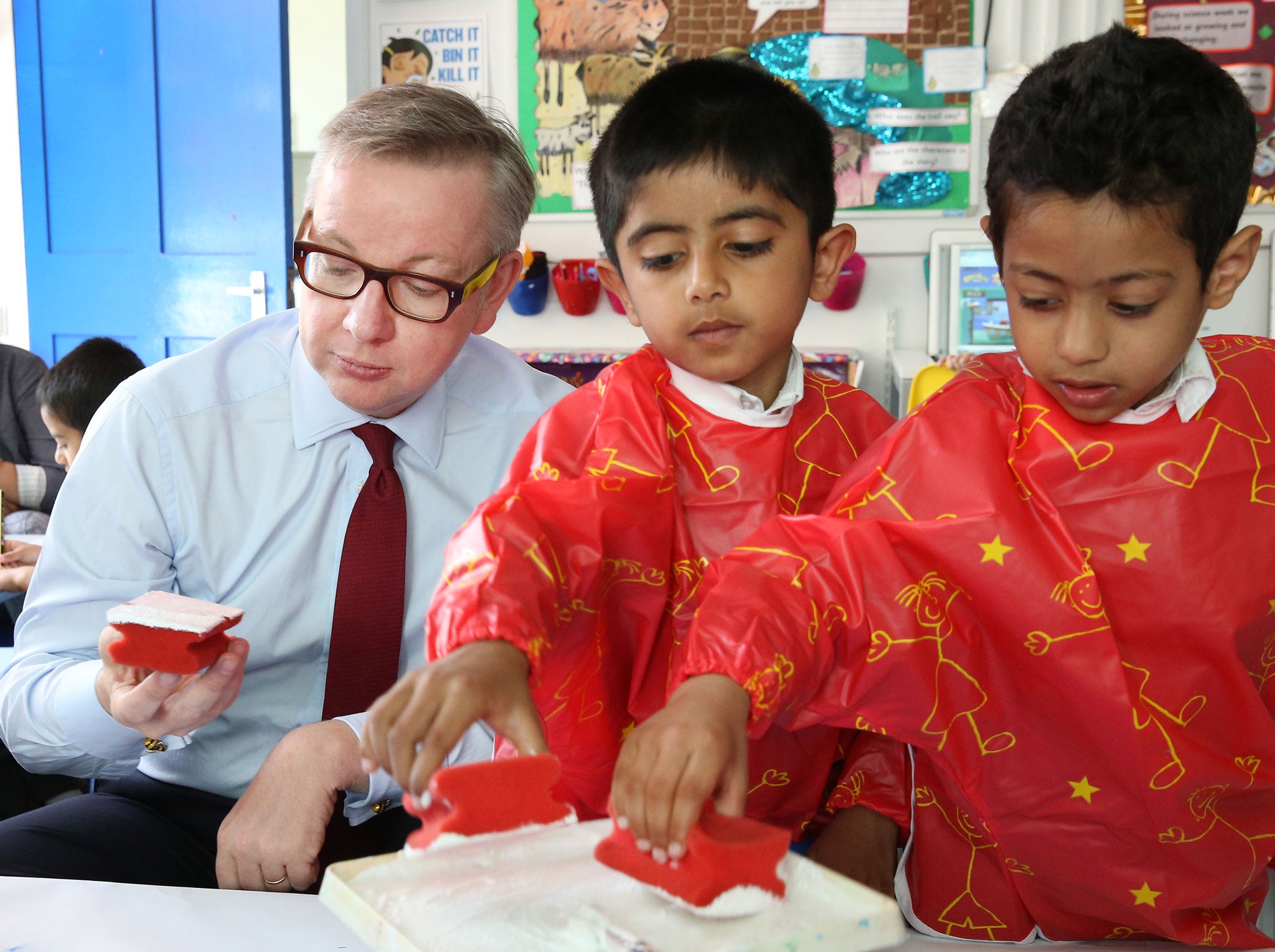 Education Secretary Michael Gove holds a paint sponge as he helps paint a picture of Canary Wharf during a visit to Old Ford Primary School