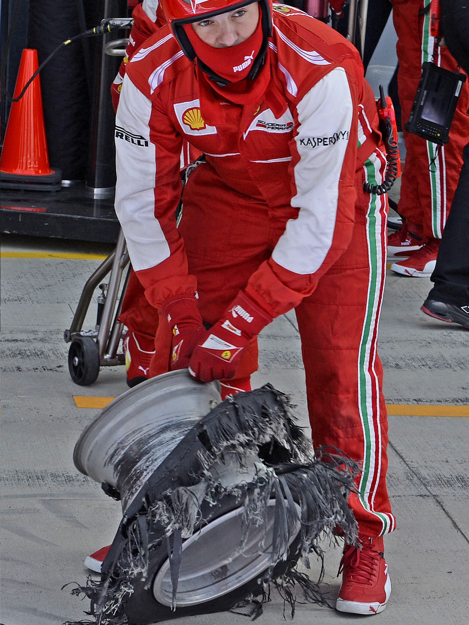 A Ferrari mechanic surveys the wreckage of Felipe Massa’s wheel