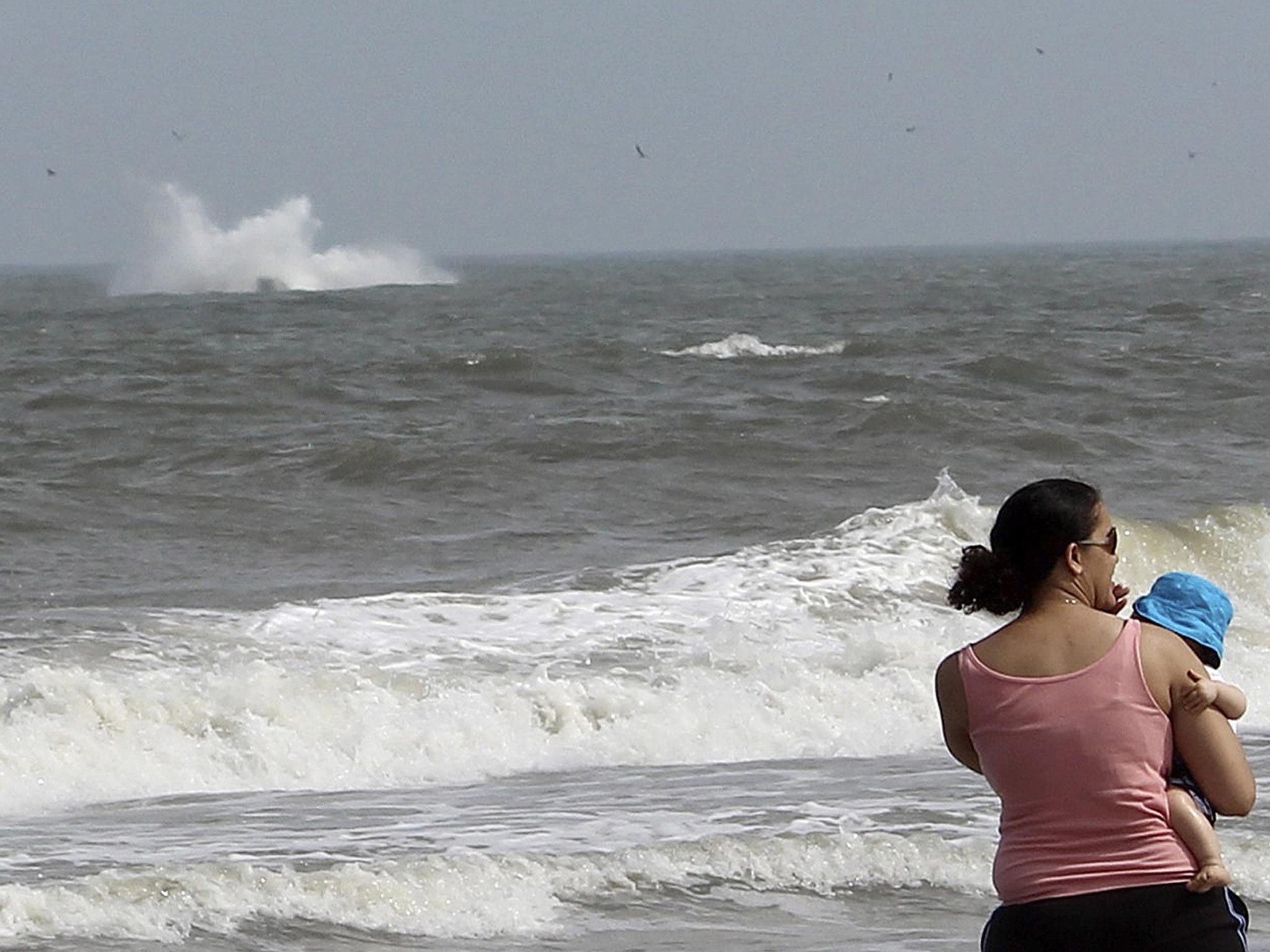 A woman holds her child as a plane crashes into the Atlantic Ocean with two off-duty police officers off the beach from Ocean City, Maryland