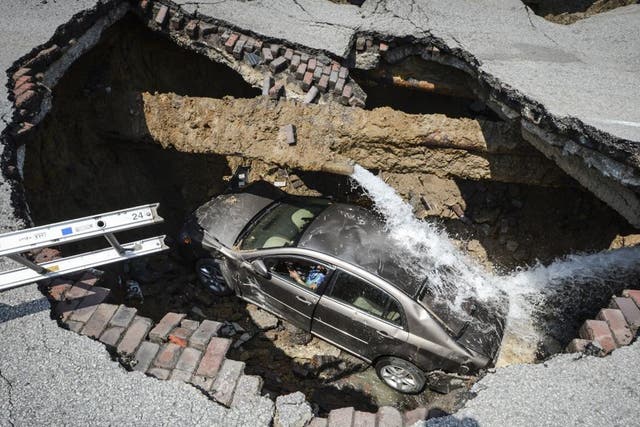 This photo provided by the Toledo, Ohio Fire and Rescue Department shows Pamela Knox's car at the bottom of a sinkhole caused by a broken water pipe in Toledo, Ohio