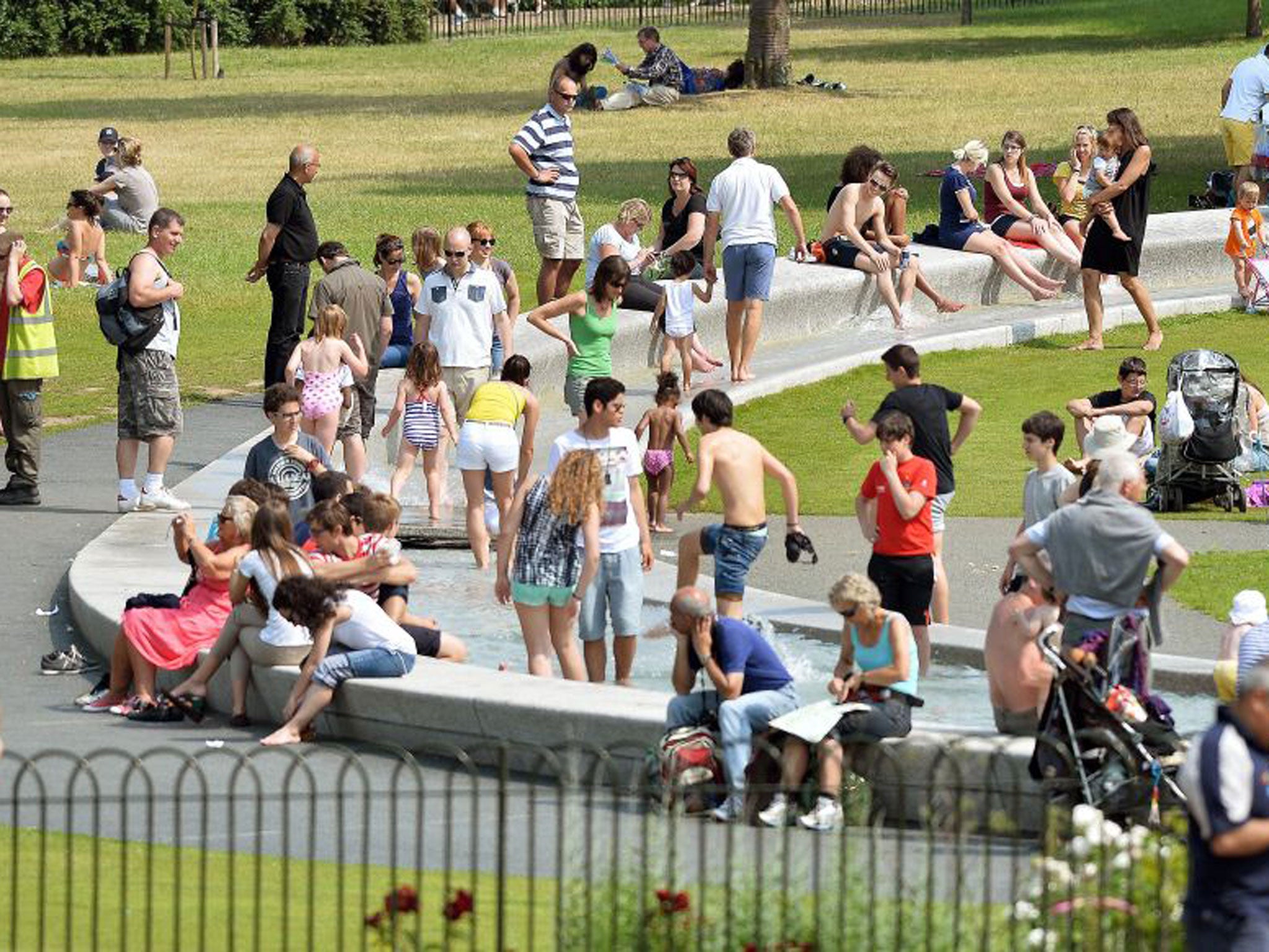 People cool off in the Diana, Princess of Wales Memorial Fountain in Hyde Park yesterday as hot weather finally hits London