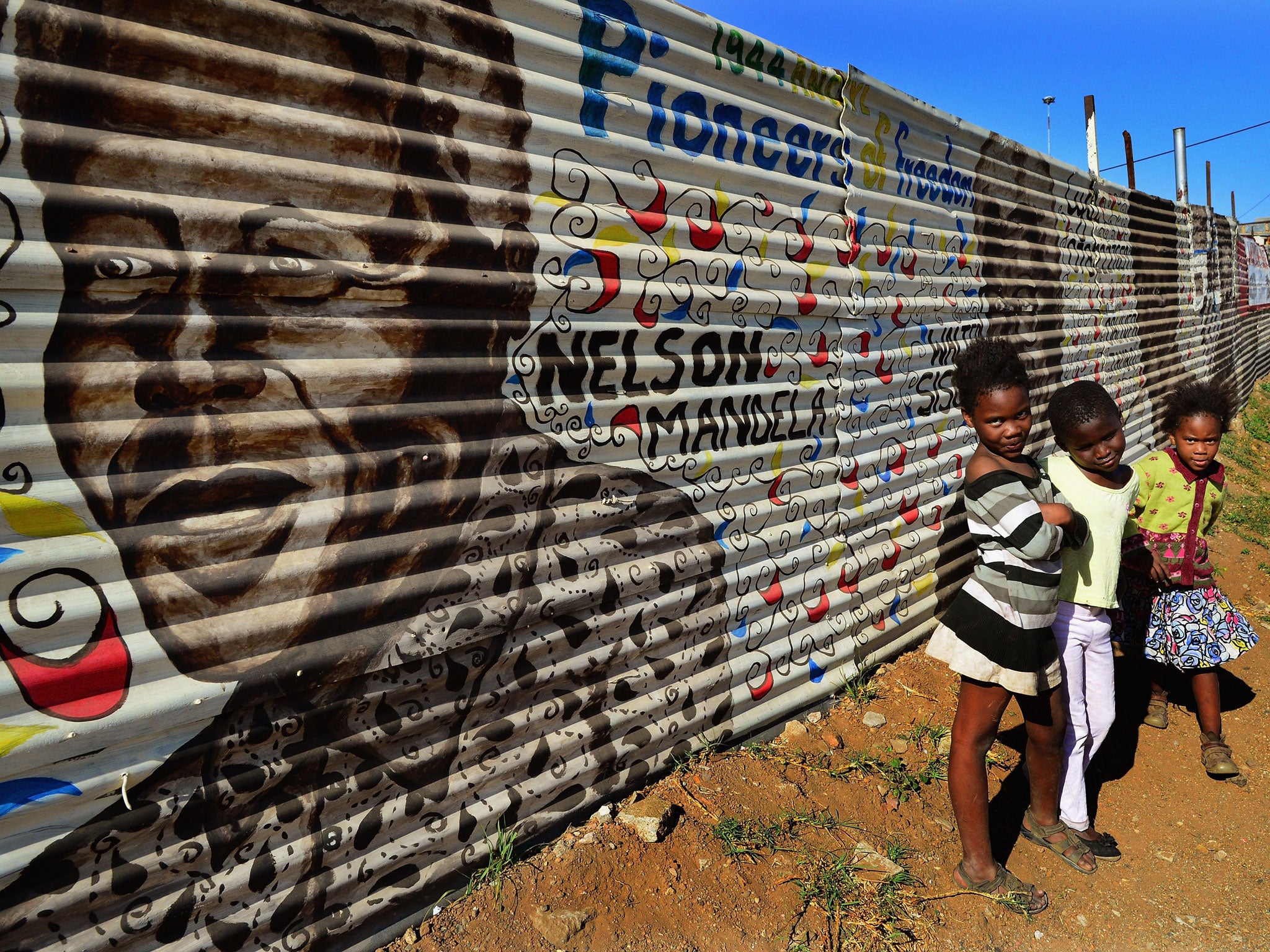 Children in Soweto in front of a mural of Nelson Mandela
