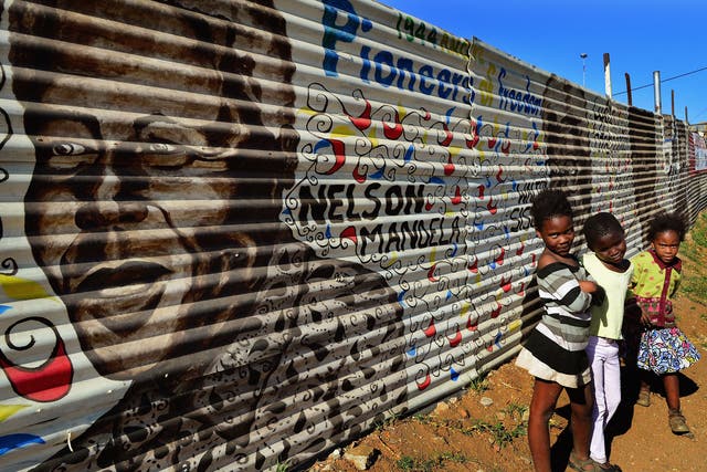 Children in Soweto in front of a mural of Nelson Mandela