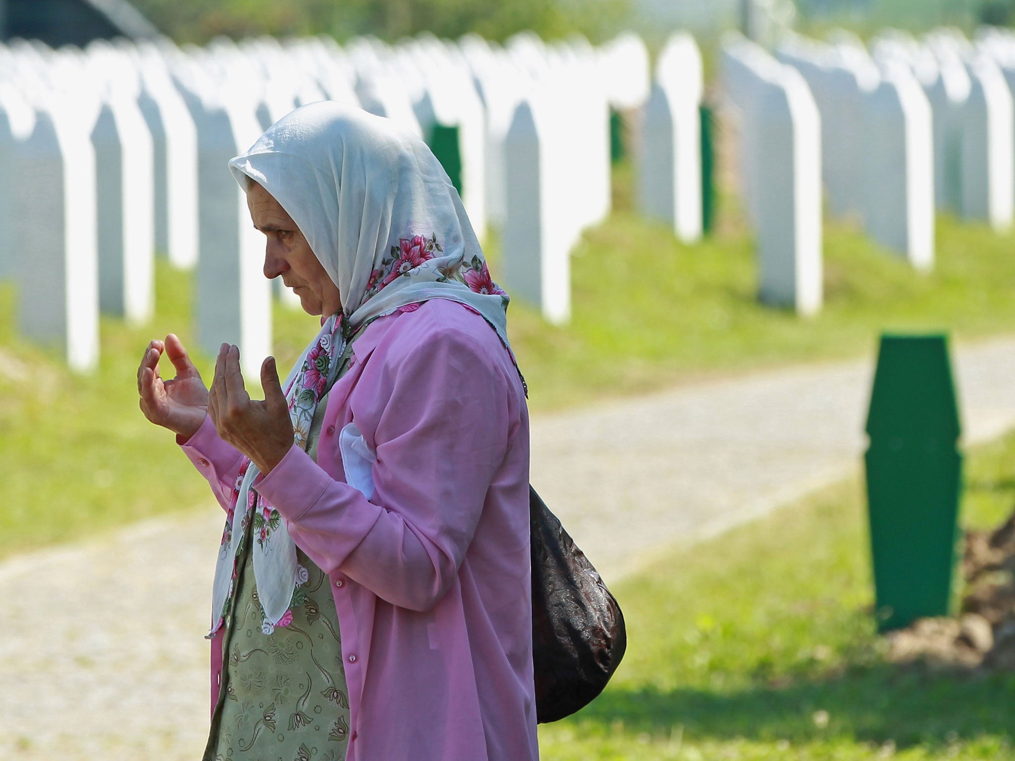 An elderly woman prays at a gravesite among the thousands of victims of the 1995 Srebrenica massacre buried at the Potocari cemetery and memorial near Srebrenica on July 9, 2011 in Potocari, Bosnia and Herzegovina.