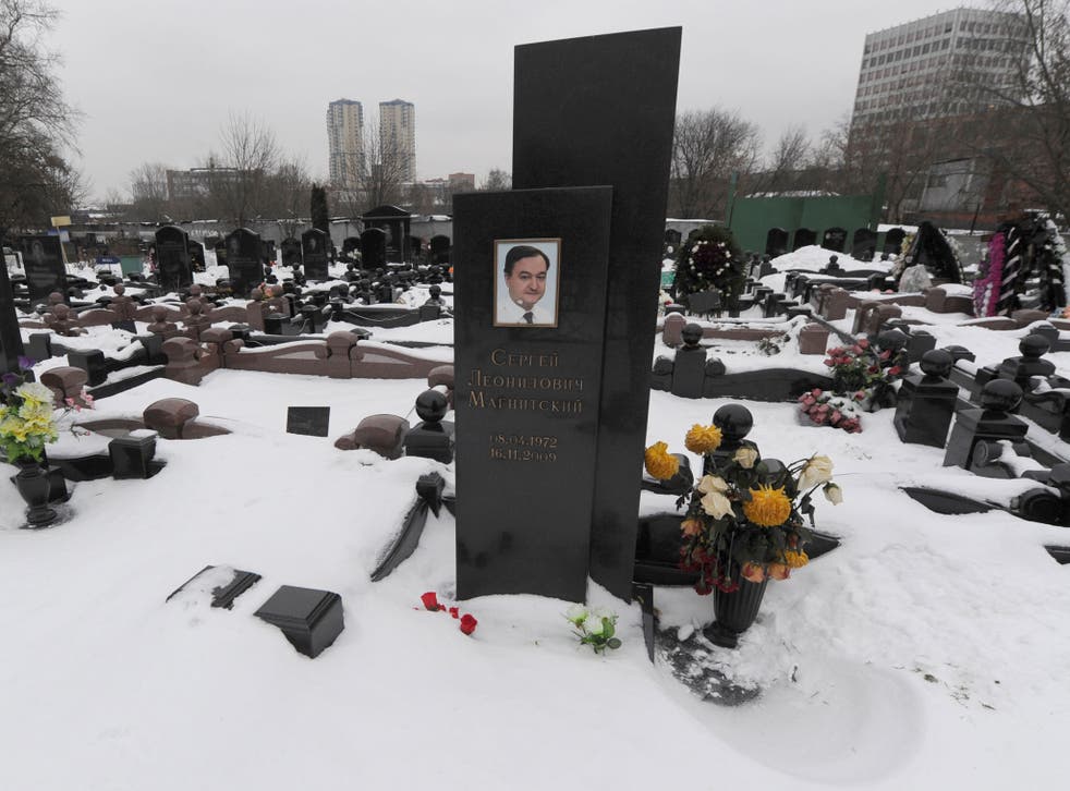 A picture taken on December 7, 2012, shows snow clad grave of Russian lawyer Sergei Magnitsky with his portrait on the tomb (C) at the Preobrazhenskoye cemetery in Moscow.