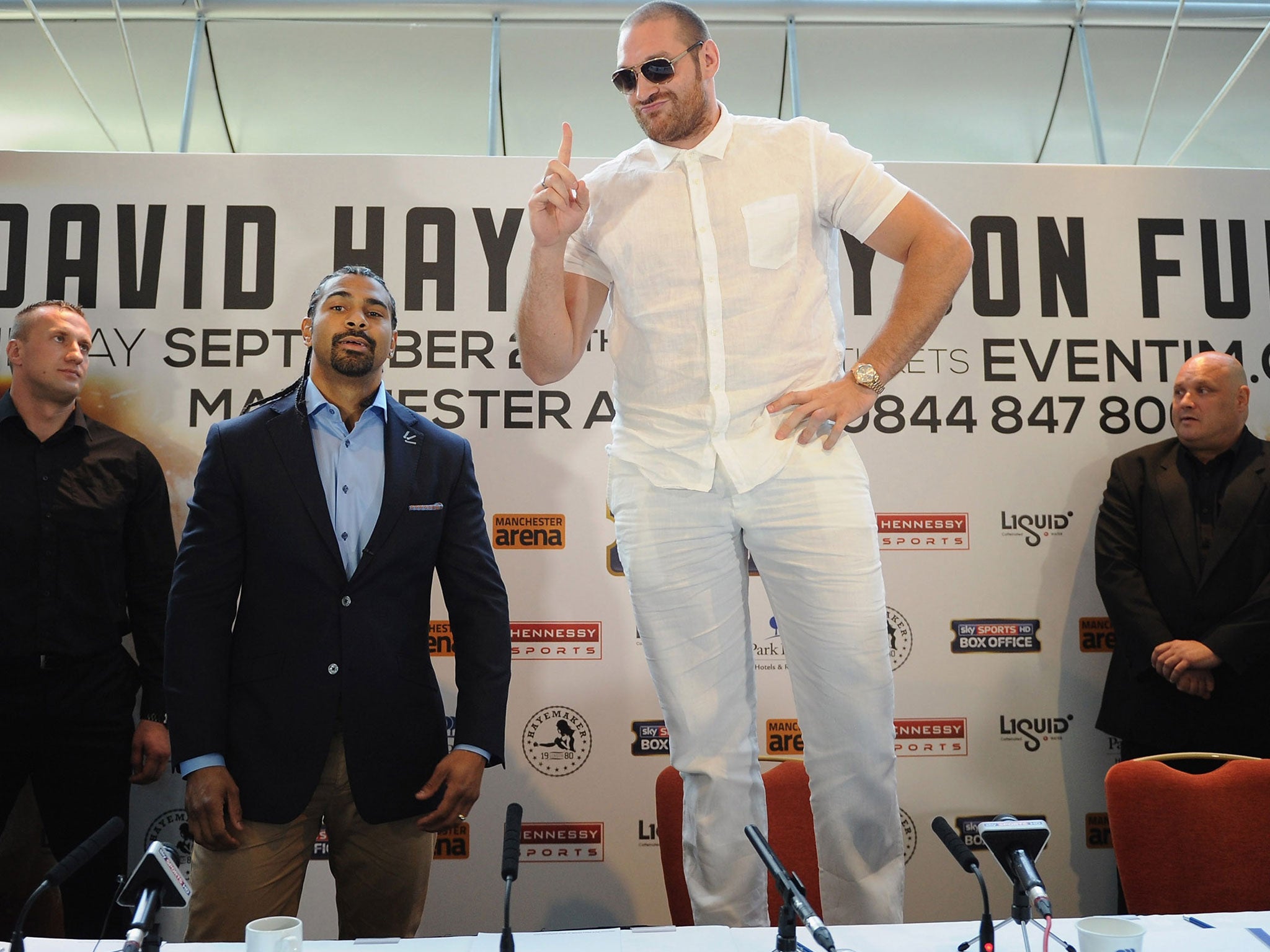 Tyson Fury stands on a chair to make a point during his press conference with David Haye