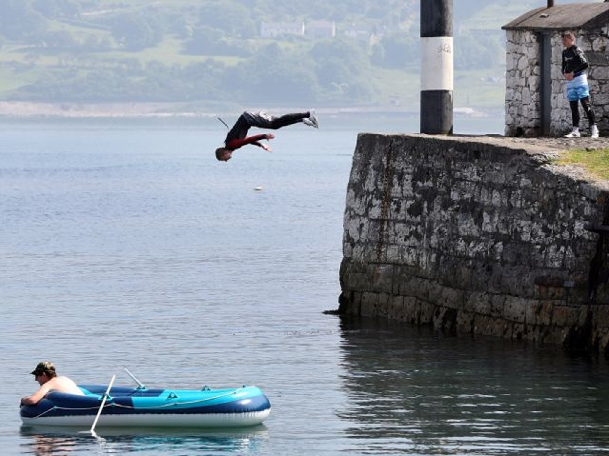 A youth jumps into the sea at Carnlogh harbour in County Antrim