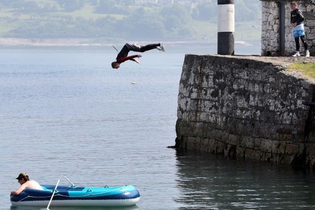 A youth jumps into the sea at Carnlogh harbour in County Antrim