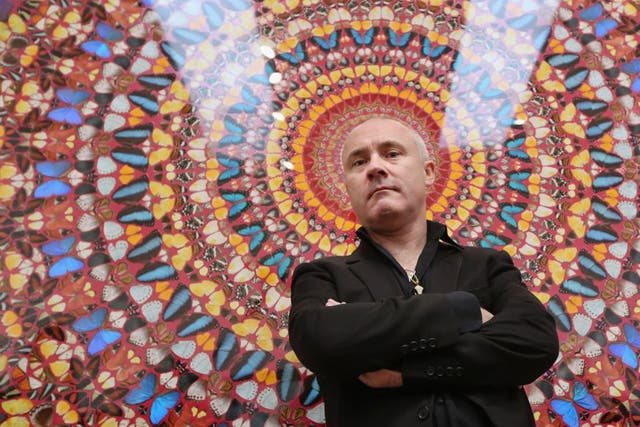 Artist Damien Hirst poses in front of his artwork entitled 'I am Become Death, Shatterer of Worlds' in the Tate Modern art gallery 