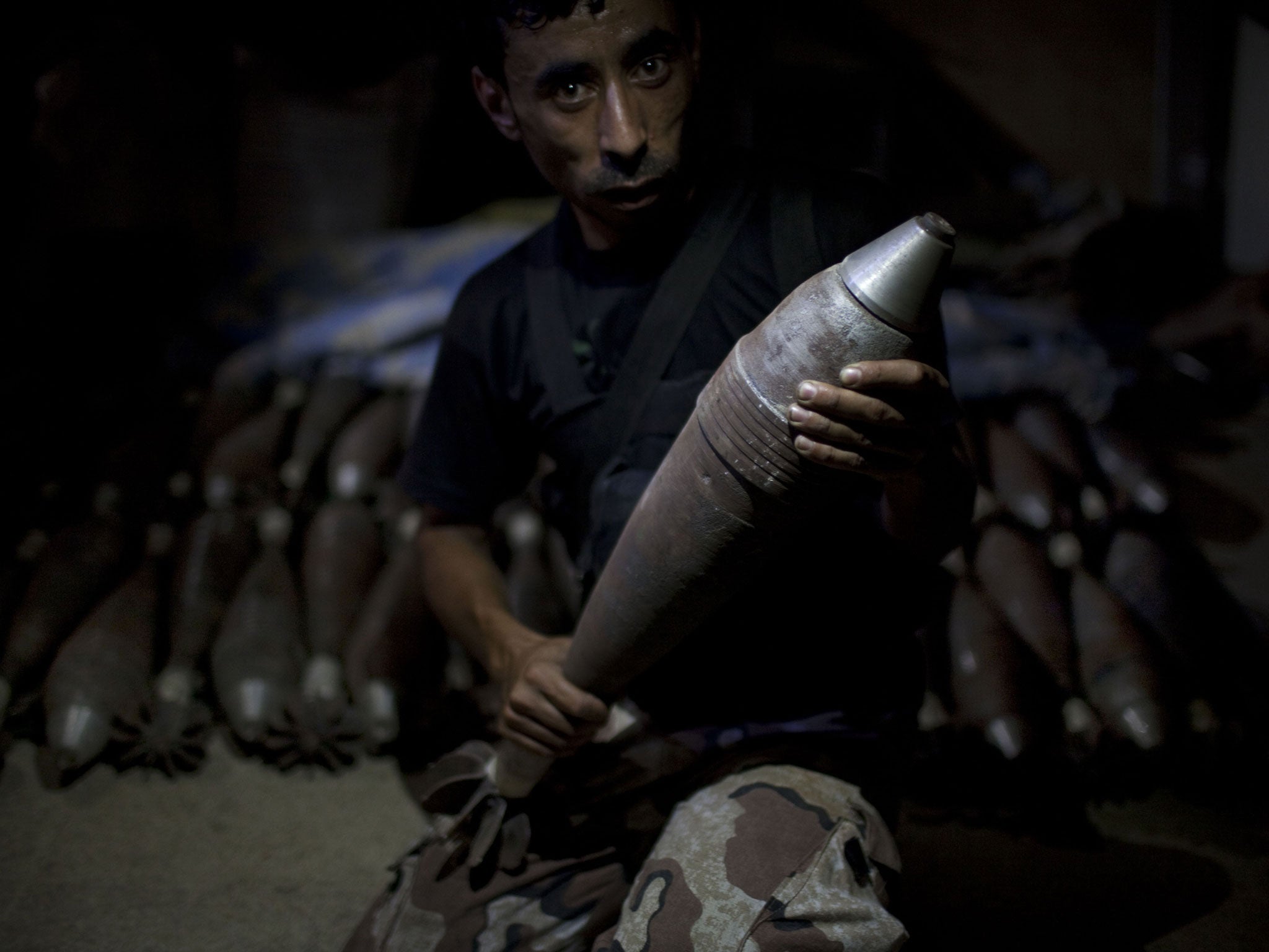 A rebel fighter holds an improvised mortar shell, one of many stacked at a factory in the city of Aleppo, Syria's commercial capital, on July 7, 2013. Syria's 27-month war between rebel forces and pro-government troops has killed more than 100,000 people, a monitoring group group estimates.