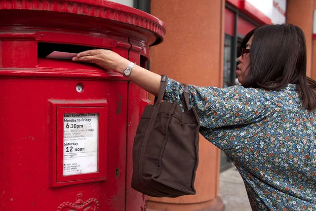 A woman posts a letter in a Royal Mail post box in London on July 10, 2013. The Government has announced plans to privatise more than half of Royal Mail.
