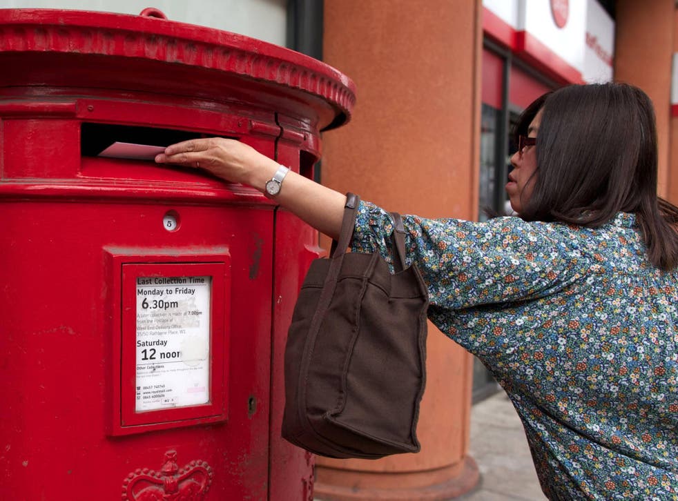 A woman posts a letter in a Royal Mail post box in London on July 10, 2013