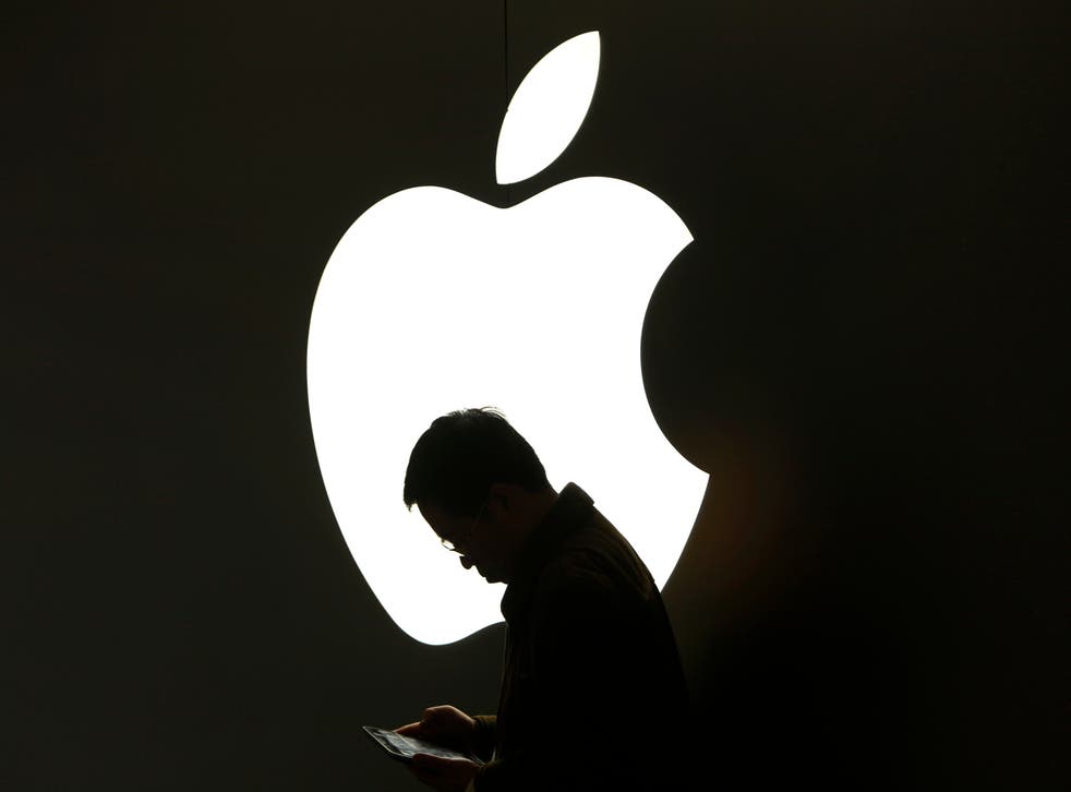A man looks at his Apple iPad in front an Apple logo outside an Apple store in downtown Shanghai March 16, 2012. REUTERS/Aly Song