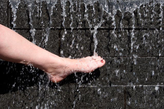 A woman cools her foot in a fountain during hot weather in Nottingham, central England May 8, 2008. REUTERS/Darren Staples