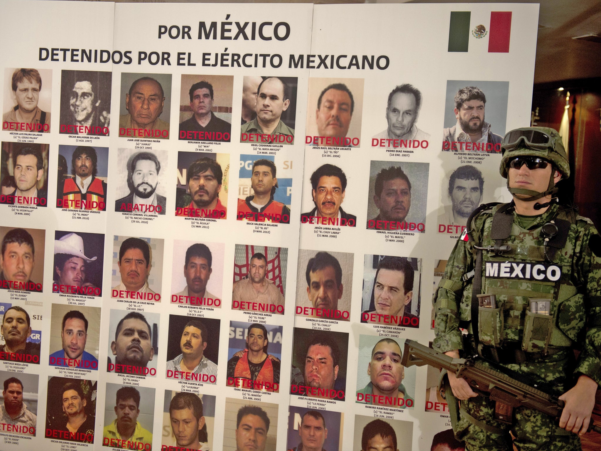A Mexican soldier stands guard beside a placard with pictures of alleged drug cartels members already arrested