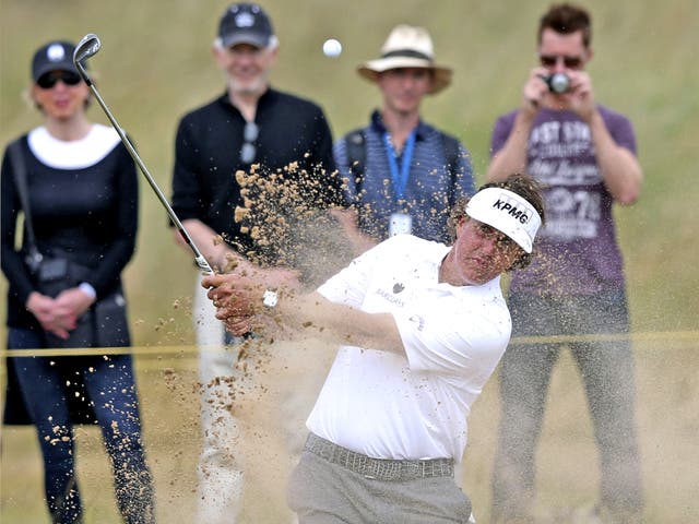 Phil Mickelson plays out of the green-side bunker on the 15th