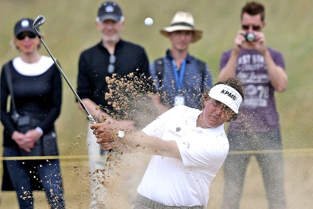 Phil Mickelson plays out of the green-side bunker on the 15th