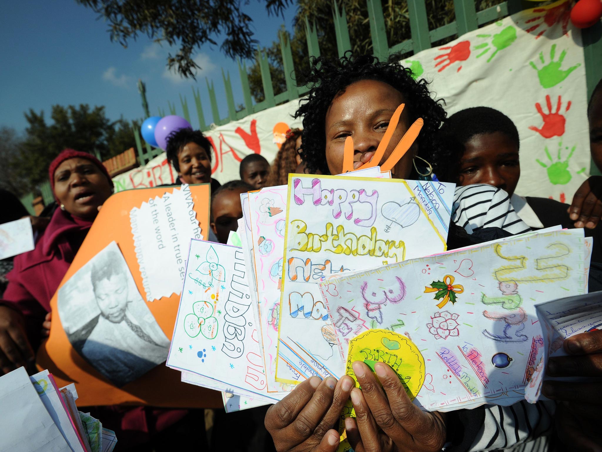 Teachers and students from The Lukho Lwen School hold cards wishing former South African Nelson Mandela a happy birthday on Mandela Day in Soweto