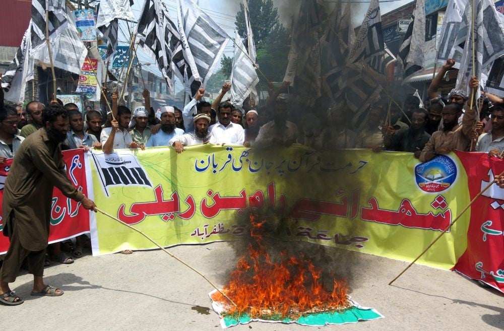 Supporters of banned Islamic charity Jamat ud Dawa burn a mock of Indian flag as they shout slogans during a protest against the killing of muslim protesters, in Muzaffarabad