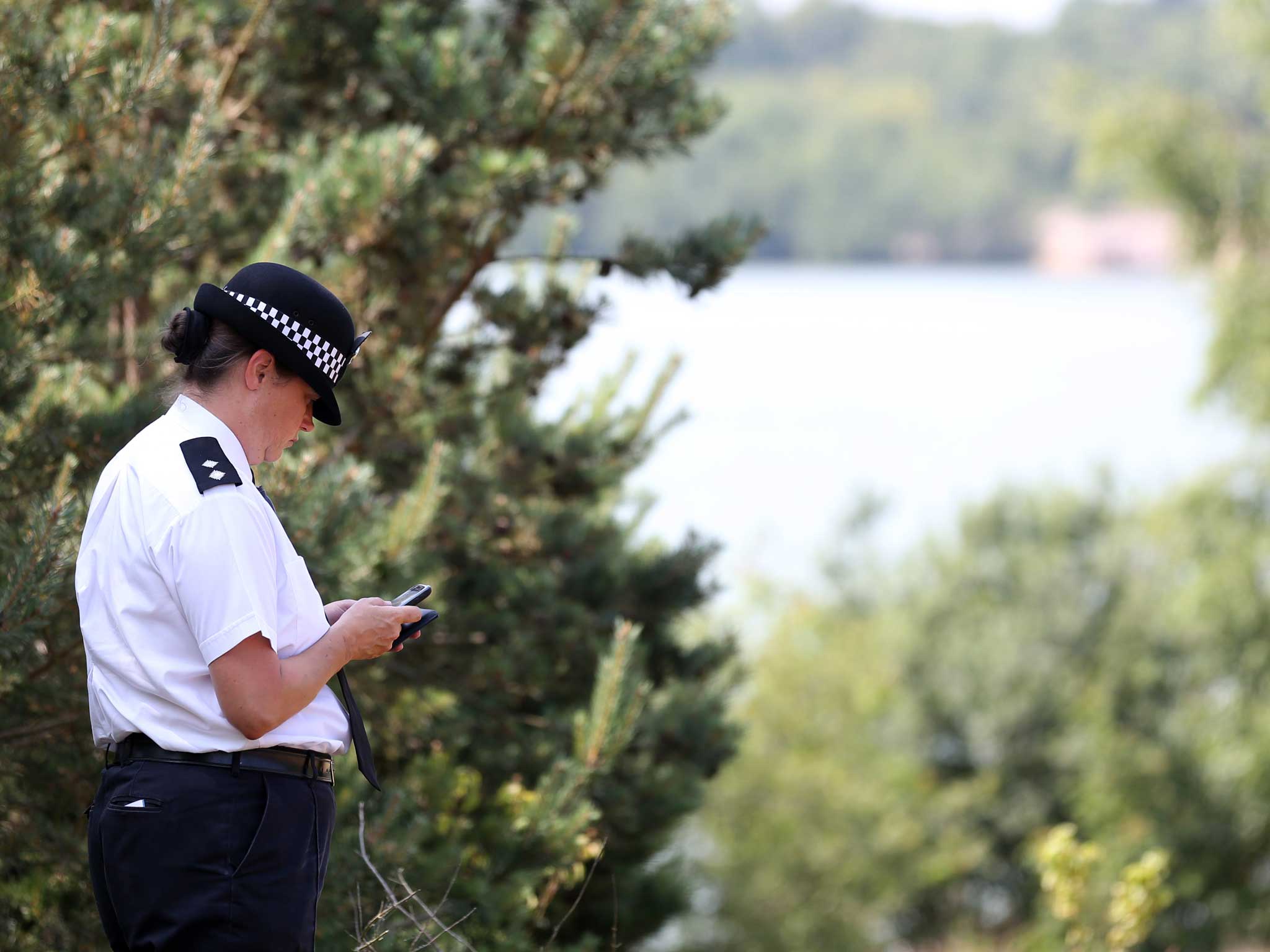 A police officer stands beside the water at Bawsey Pits