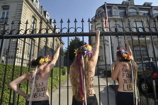 22 July 2013: Members of Femen Belgium shout slogans outside the gates of the Tunisian embassy after they used a chain to lock the gates, during a protect calling for the release of fellow activist Tunisian Amina Tyler, in Brussels
