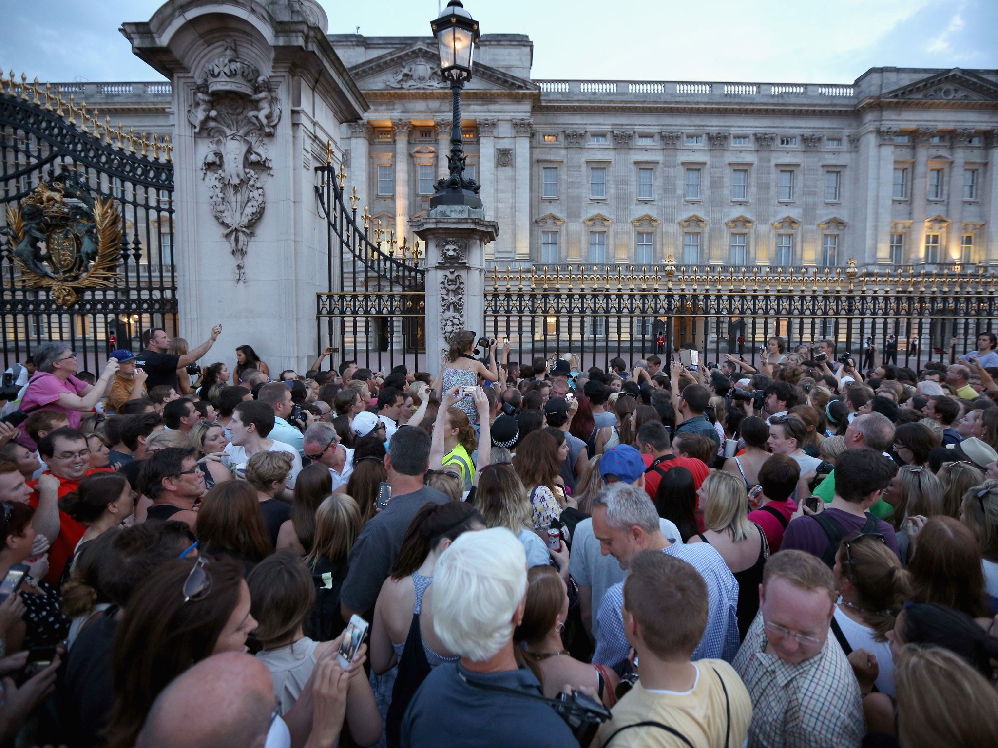 A crowd of people take photos of the easel in front of the palace