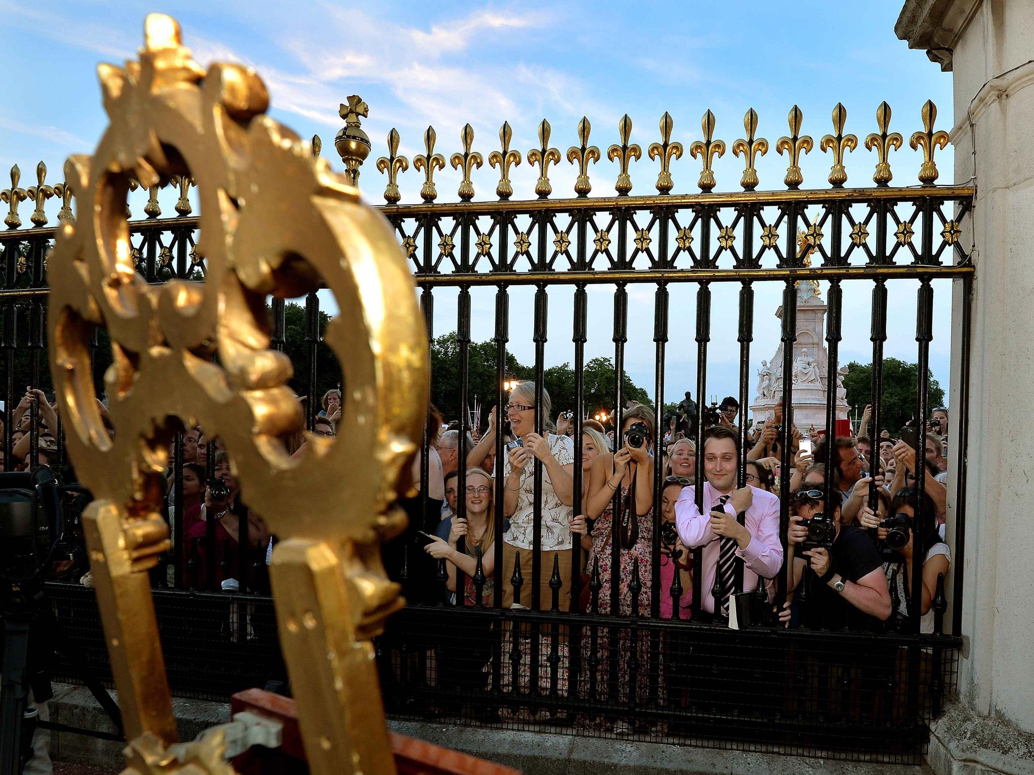 Crowds of people try to look at a notice formally announcing the birth of a son to the Duke and Duchess of Cambridge, placed in the forecourt of Buckingham Palace