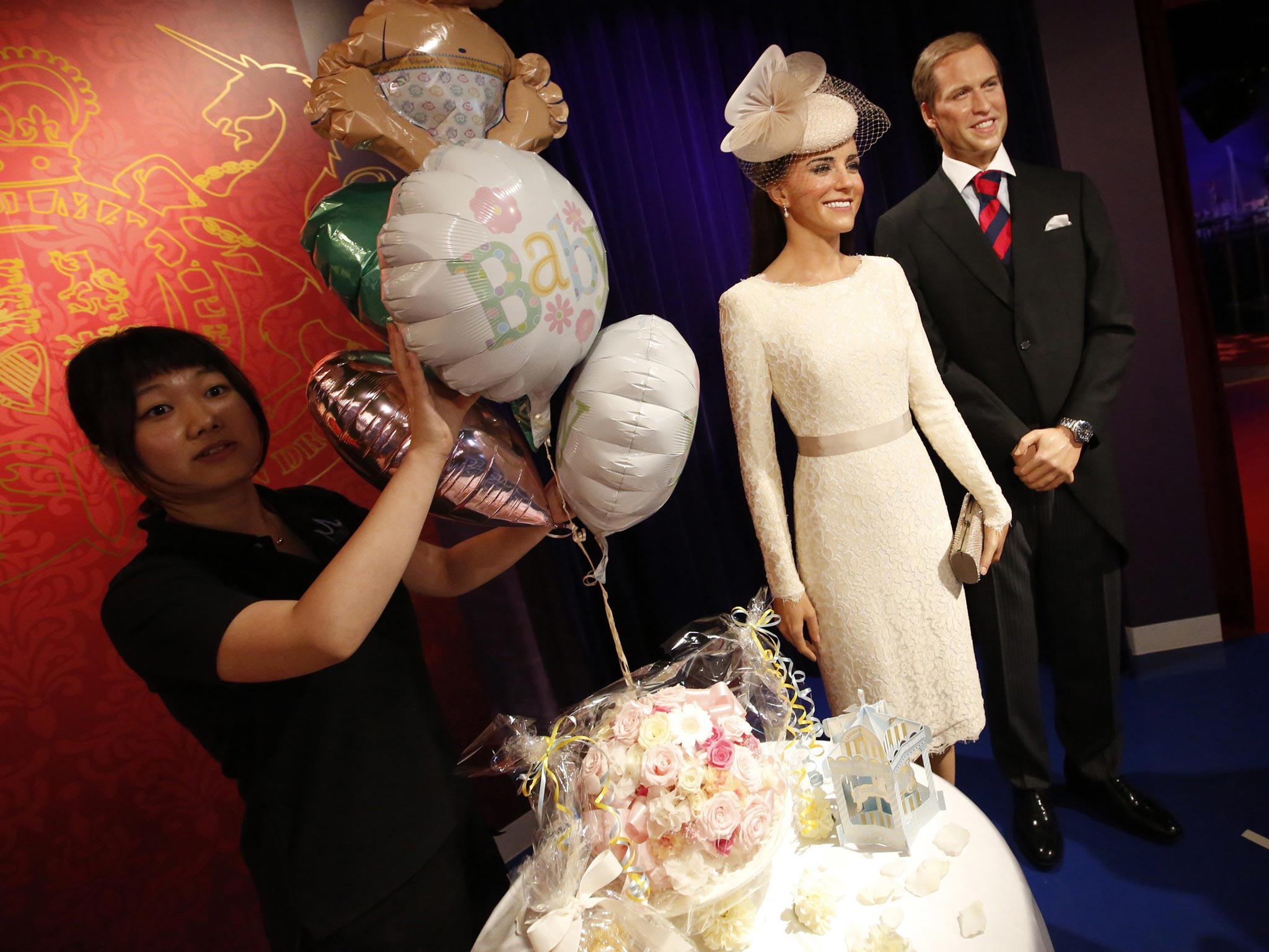 A staff member of the Madame Tussauds Tokyo wax museum prepares decorations next to the wax figures of Britain's Prince William and his wife Catherine