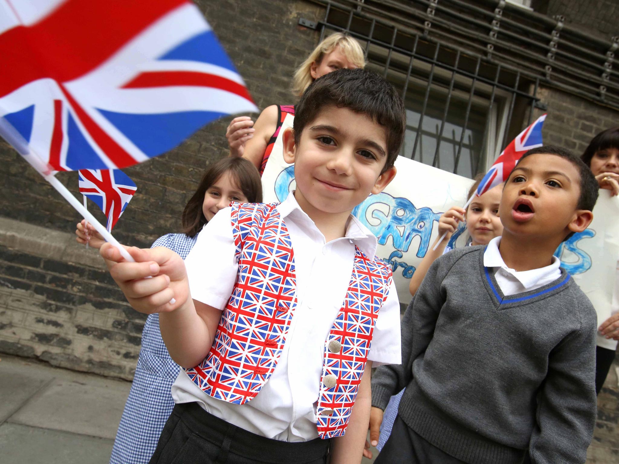 School children wave flags in celebration of the birth of the royal baby outside St. Mary's hospital