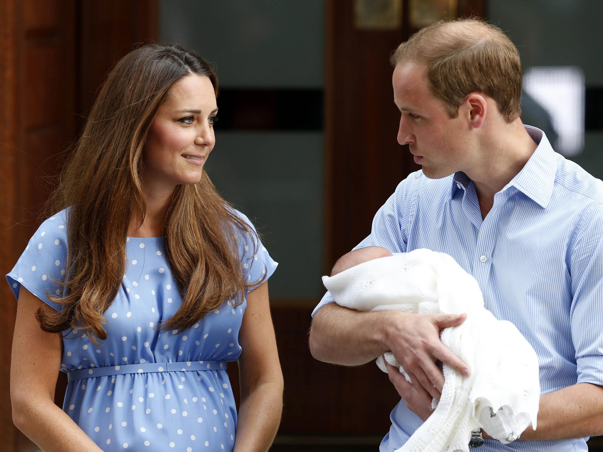 The Duke and Duchess of Cambridge hold Prince George as he makes his first public appearance in July 2013