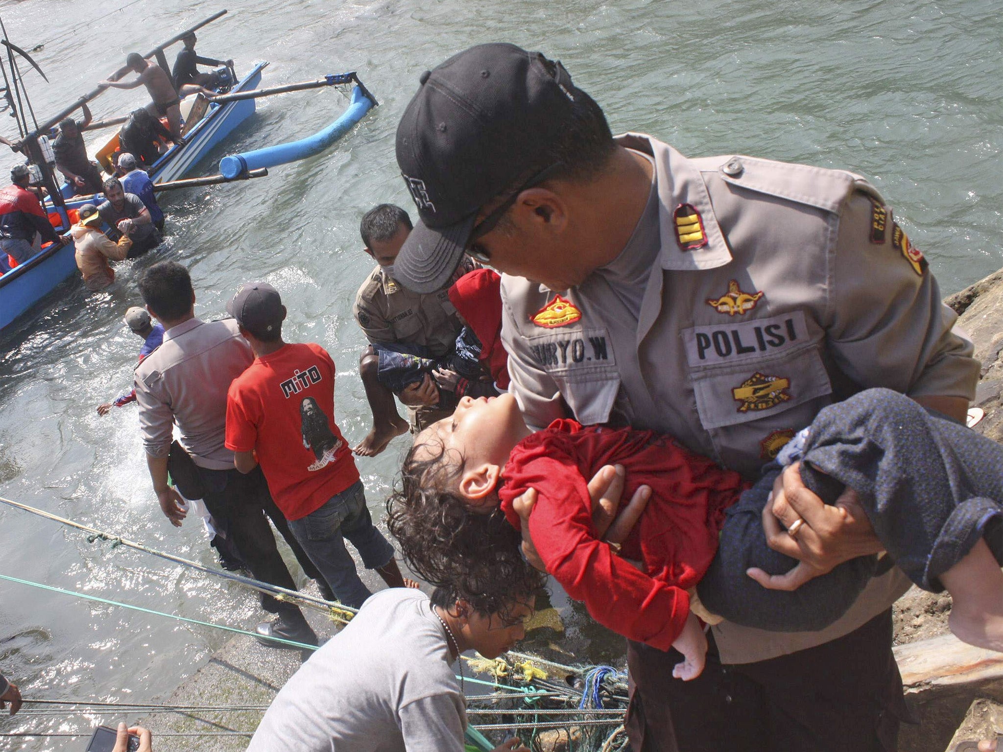 A police officer carries a child survivor who was on the boat full of asylum seekers that capsized off the coast of Sukapura, Indonesia. Nine people died but 189 refugees were rescued