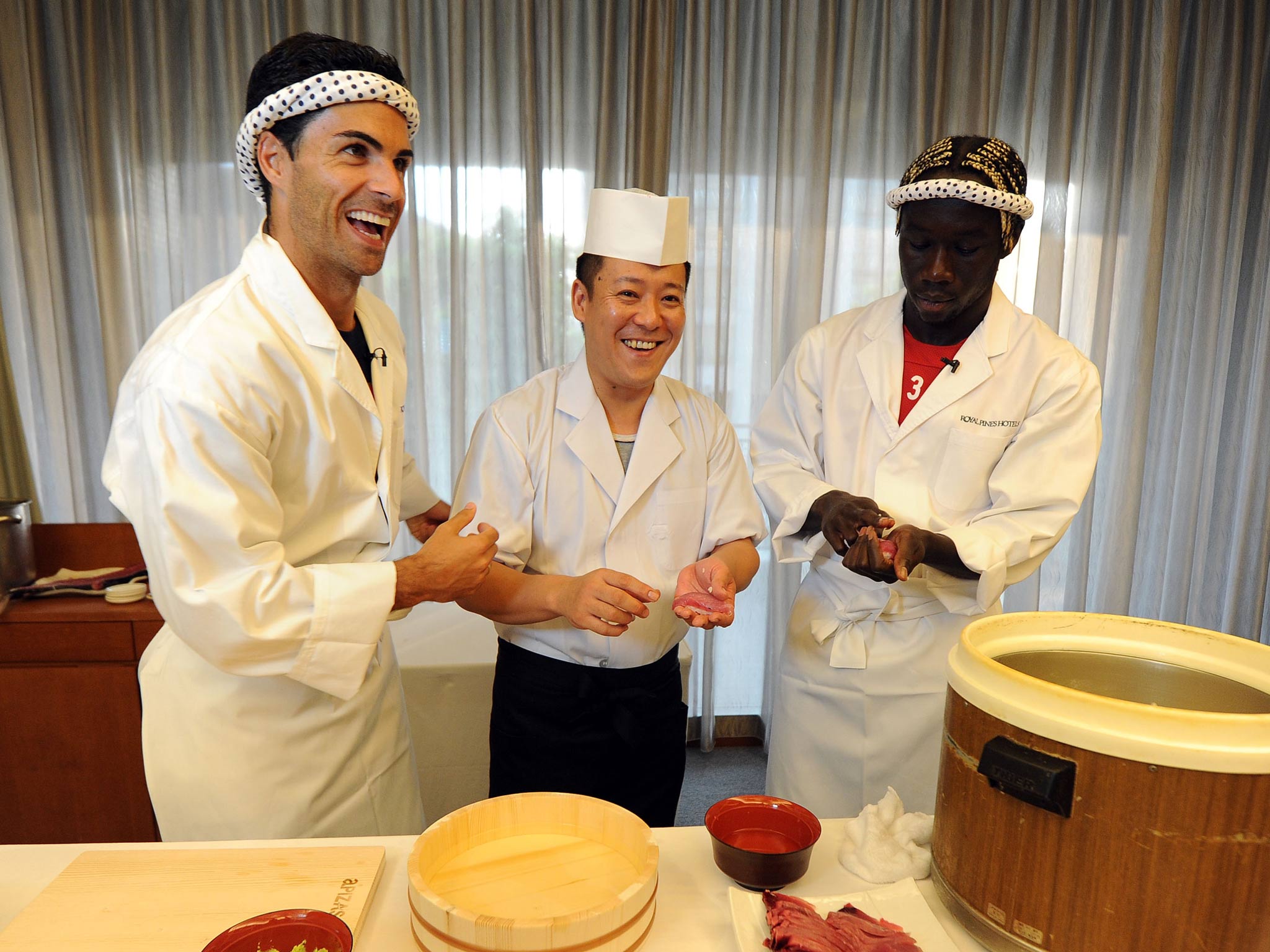 Mikel Arteta (L) and Bacary Sagna (R) of Arsenal FC are given a lesson in making Sushi from a top Sushi Chef in the Urawa Royal Pines Hotel in Japan