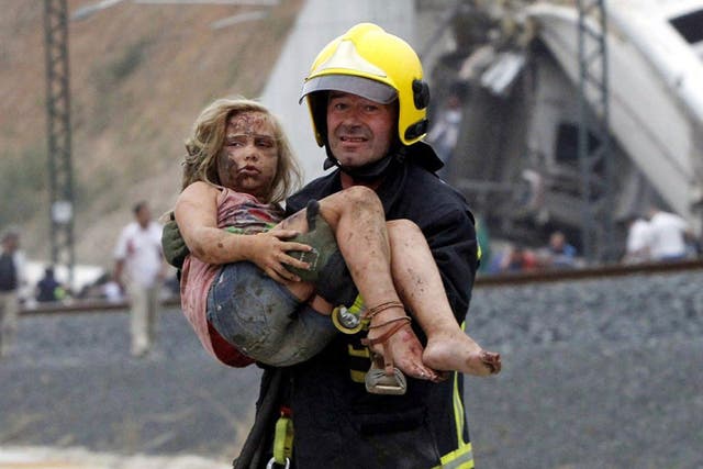 An injured girl is carried from the wreckage of the crash near Santiago de Compostela