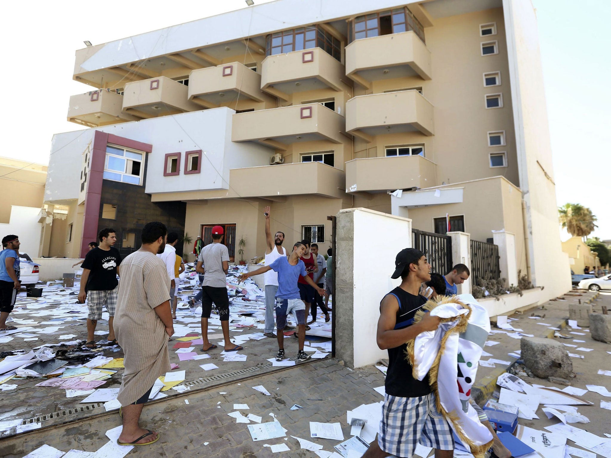 Libyan protesters stand amidst scattered documents after ransacking the headquarters of the liberal National Forces Alliance (NFA), the country's biggest political party founded by wartime rebel prime minister Mahmoud Jibril